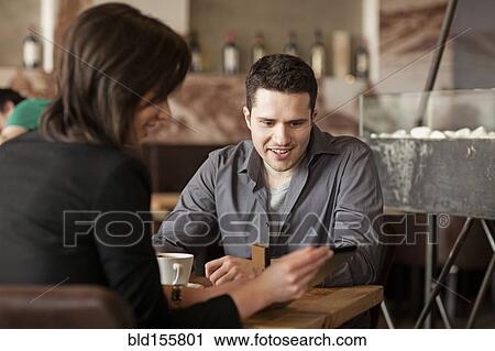 Stock Image - Couple using cell phone in cafe. Fotosearch