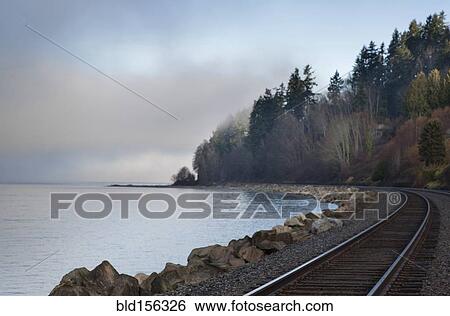 Empty train tracks around rural ocean bay View Large Photo Image Stock Photograph - Empty train tracks around rural ocean bay. Fotosearch