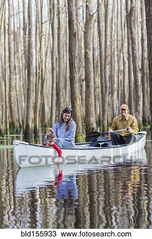 Stock Image - Family sitting together in canoe on river. Fotosearch