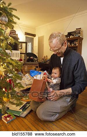 Stock Photo - Father and baby boy opening Christmas gifts. Fotosearch