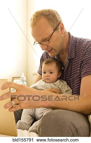Stock Image - Father reading to baby boy. Fotosearch