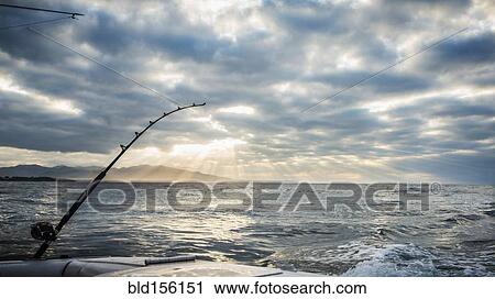 Stock Image - Fishing poles on boat over ocean waves. Fotosearch