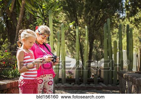 Stock Image - Girls looking at digital camera photographs on vacation. Fotosearch