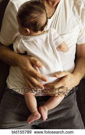 Stock Photo - High angle view of father holding baby boy. Fotosearch