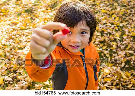 Stock Photography - High angle view of mixed race boy holding berry. Fotosearch