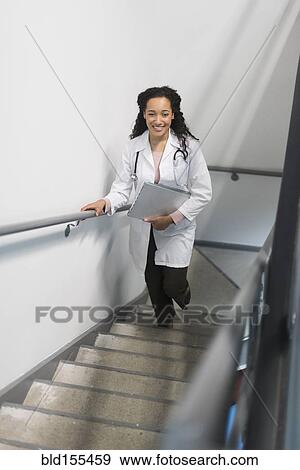 Stock Photo - High angle view of mixed race doctor climbing staircase. Fotosearch