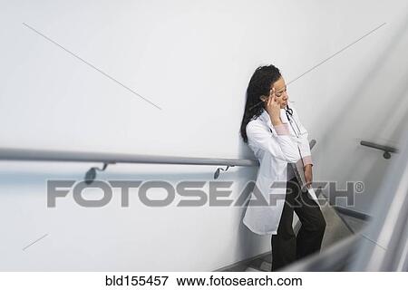 Stock Photo - High angle view of stressed mixed race doctor standing on staircase. Fotosearch
