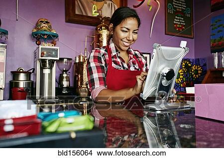 Hispanic barista using digital tablet register in coffee shop View Large Photo Image Picture - Hispanic barista using digital tablet register in coffee shop. Fotosearch