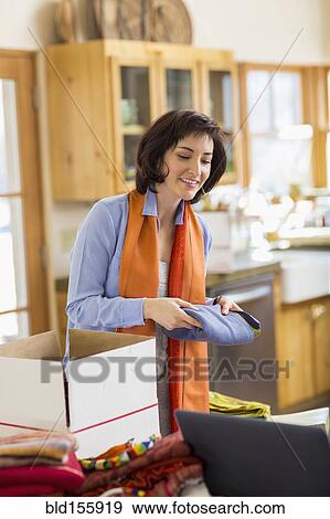Stock Photo - Hispanic business owner packing boxes in home office. Fotosearch