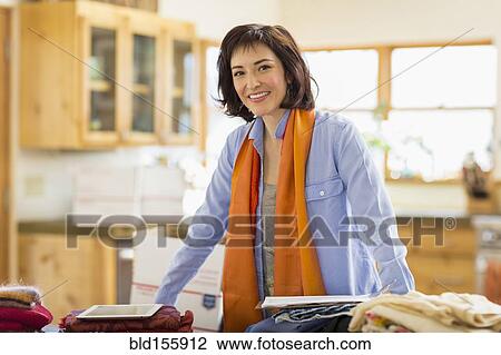 Stock Image - Hispanic business owner smiling in home office. Fotosearch