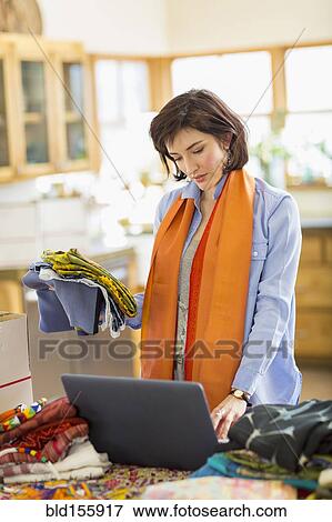 Stock Photo - Hispanic business owner using laptop in home office. Fotosearch