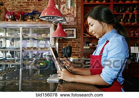 Hispanic cashier using digital tablet register in bakery View Large Photo Image Stock Photo - Hispanic cashier using digital tablet register in bakery. Fotosearch