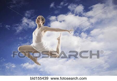 Stock Photo - Hispanic dancer leaping in cloudy blue sky. Fotosearch