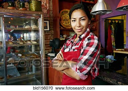 Stock Image - Hispanic waitress smiling in bakery. Fotosearch