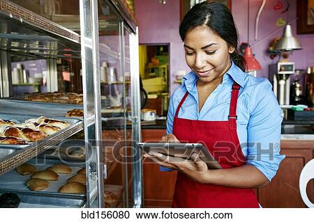 Hispanic waitress taking inventory with digital tablet in bakery View Large Photo Image Stock Image - Hispanic waitress taking inventory with digital tablet in bakery. Fotosearch