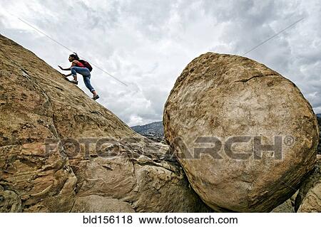 Stock Photo - Hispanic woman climbing rocky hillside. Fotosearch