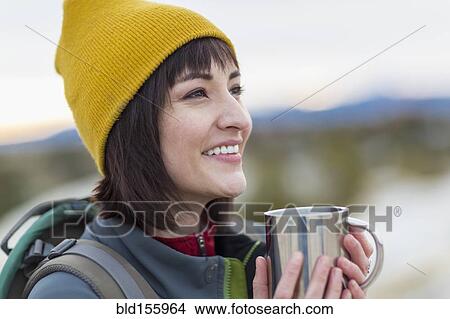 Picture - Hispanic woman drinking coffee outdoors. Fotosearch