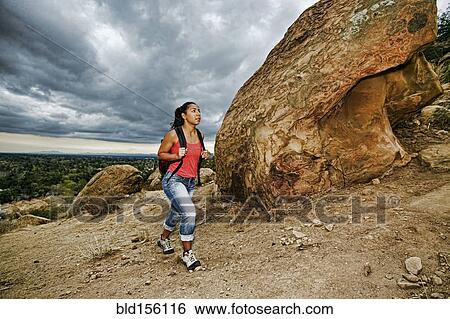Stock Photograph - Hispanic woman hiking on rocky hillside. Fotosearch