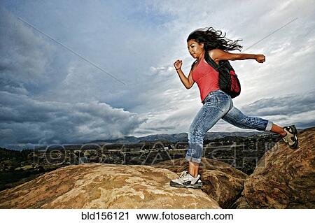 Hispanic woman jumping crevasse on rock formation View Large Photo Image Stock Image - Hispanic woman jumping crevasse on rock formation. Fotosearch
