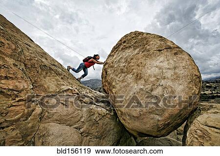 Hispanic woman pushing boulder on rocky hillside View Large Photo Image Stock Photo - Hispanic woman pushing boulder on rocky hillside. Fotosearch