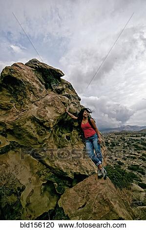Stock Image - Hispanic woman standing on rock formation. Fotosearch