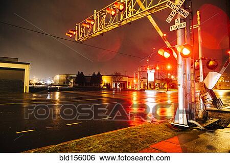 Stock Photograph - Illuminated traffic lights on railroad crossing at night. Fotosearch