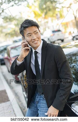 Korean businessman talking on cell phone near car View Large Photo Image Stock Image - Korean businessman talking on cell phone near car. Fotosearch