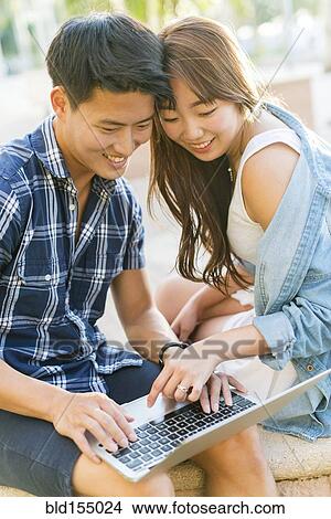 Korean couple using laptop outdoors View Large Photo Image Picture - Korean couple using laptop outdoors. Fotosearch