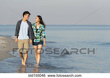 Korean couple walking in waves on beach View Large Photo Image Stock Photograph - Korean couple walking in waves on beach. Fotosearch