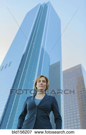 Low angle view of Caucasian businesswoman under high rise buildings View Large Photo Image Stock Photo - Low angle view of Caucasian businesswoman under high rise buildings. Fotosearch