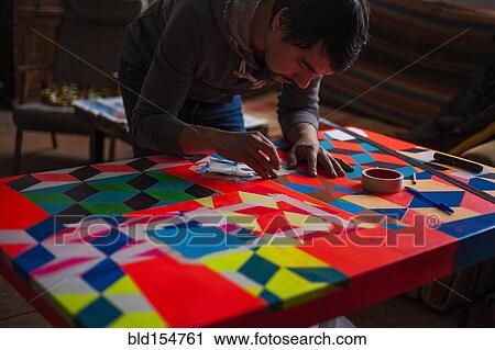 Stock Image - Mari man designing colorful table. Fotosearch