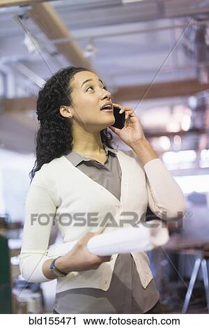 Stock Image - Mixed race architect talking on cell phone. Fotosearch