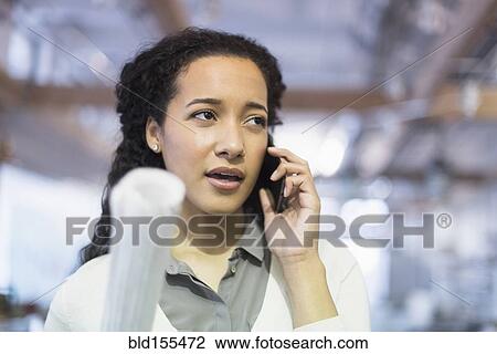 Stock Image - Mixed race architect talking on cell phone. Fotosearch