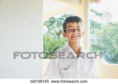 Stock Image - Mixed race boy smiling on porch. Fotosearch