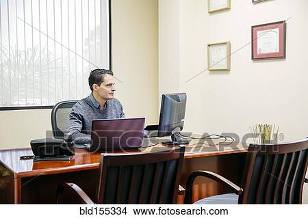 Picture - Mixed race businessman sitting in office. Fotosearch