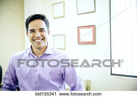Stock Image - Mixed race businessman smiling in office. Fotosearch