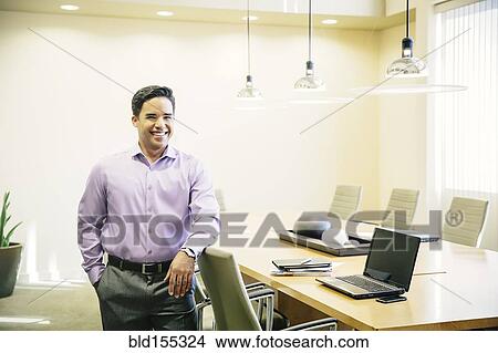 Picture - Mixed race businessman smiling in conference room. Fotosearch