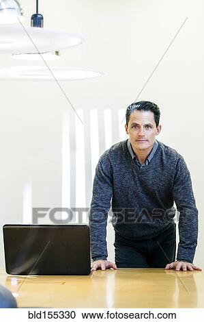 Stock Image - Mixed race businessman standing at conference table. Fotosearch
