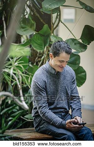 Stock Image - Mixed race businessman using cell phone in office courtyard. Fotosearch