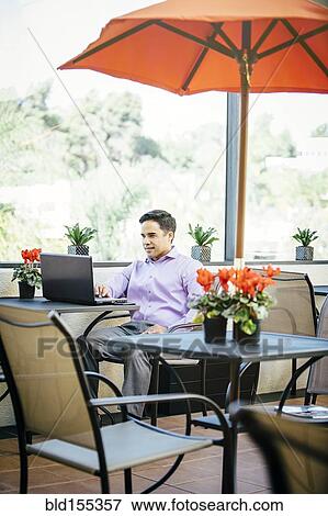 Stock Photo - Mixed race businessman working in cafe. Fotosearch