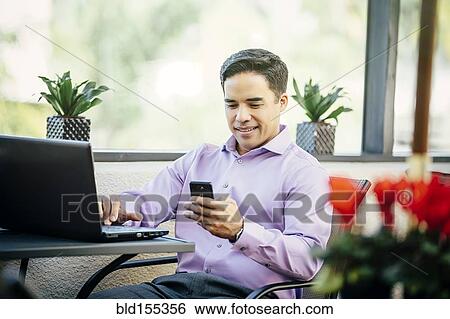 Stock Photograph - Mixed race businessman working in cafe. Fotosearch