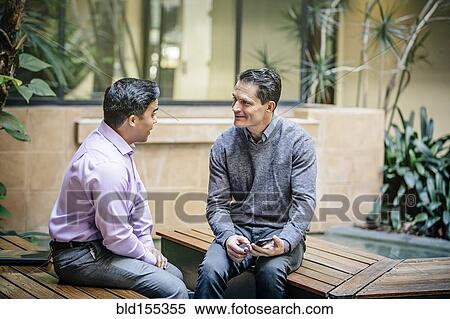 Mixed race businessmen talking in office courtyard View Large Photo Image Stock Photography - Mixed race businessmen talking in office courtyard. Fotosearch
