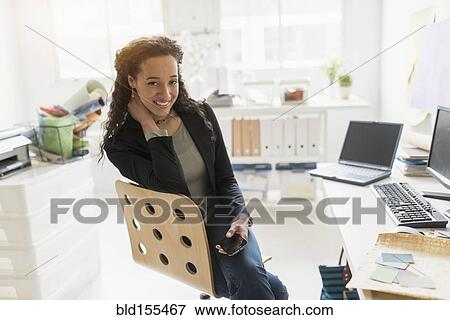 Mixed race businesswoman smiling at desk View Large Photo Image Stock Photo - Mixed race businesswoman smiling at desk. Fotosearch