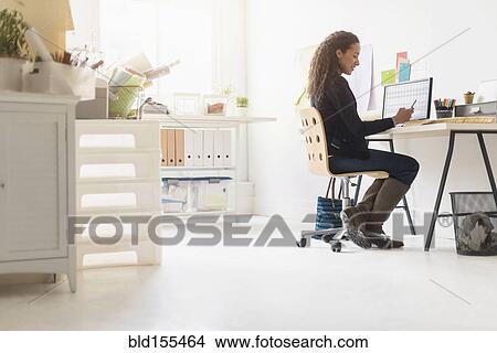 Mixed race businesswoman using cell phone at desk View Large Photo Image Picture - Mixed race businesswoman using cell phone at desk. Fotosearch