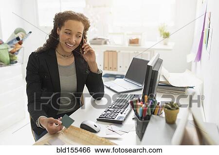Stock Photograph - Mixed race businesswoman working at desk. Fotosearch