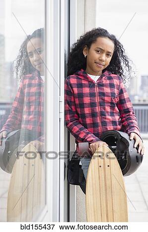 Stock Photo - Mixed race girl standing with skateboard outdoors. Fotosearch