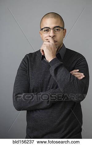 Stock Photo - Mixed race man holding chin in hand. Fotosearch