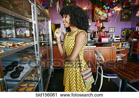 Stock Image - Mixed race woman buying pastries in bakery. Fotosearch