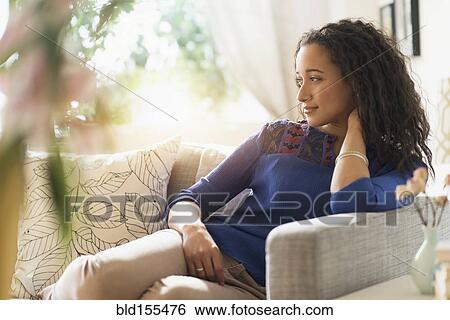 Mixed race woman smiling on sofa View Large Photo Image Stock Photograph - Mixed race woman smiling on sofa. Fotosearch