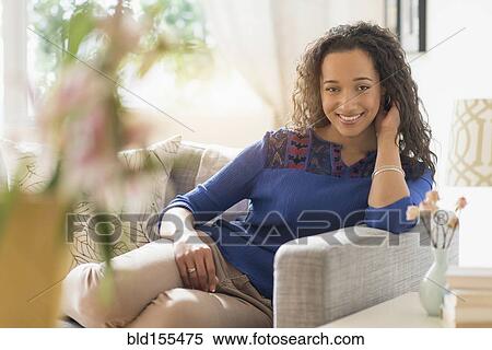 Stock Photography - Mixed race woman smiling on sofa. Fotosearch